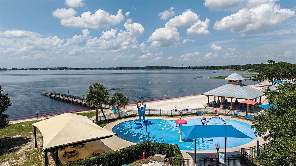 An aerial view of a lakeside park featuring a splash pad, pavilion, and wooden pier — 383 CORNERSTONE DRIVE, GROVELAND, FL