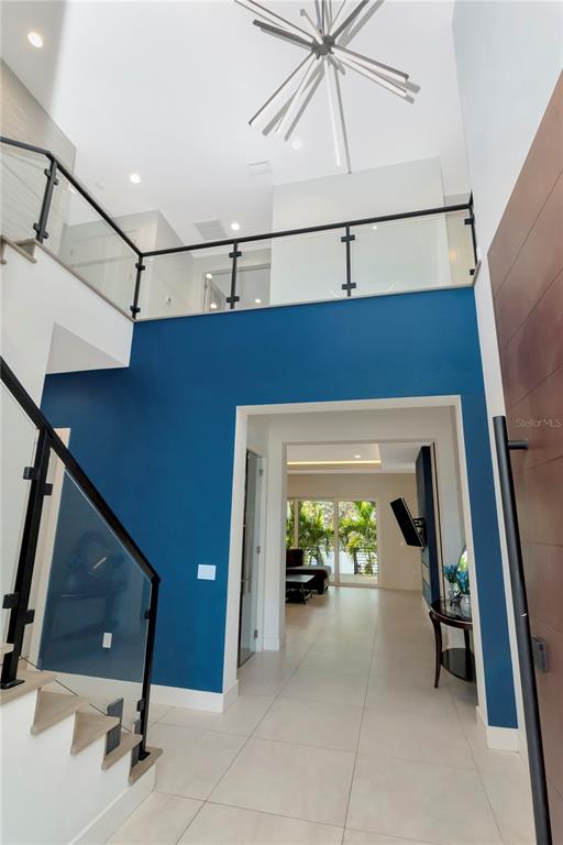 A modern foyer features a blue accent wall, glass-railed staircase, and a high ceiling — 4604 W LOWELL AVENUE, TAMPA, FL