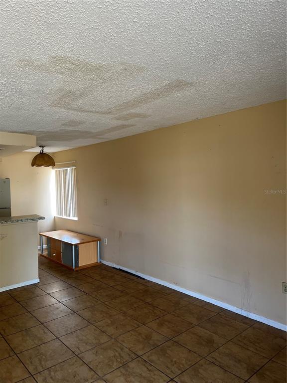 An interior room features tiled flooring, beige walls, and a ceiling with water damage stains — 800 N FISKE BOULEVARD UNIT 606, COCOA, FL