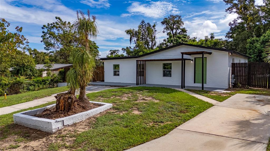A white single-story house features a green front door and a concrete driveway — 5621 LUNSFORD DRIVE, ORLANDO, FL