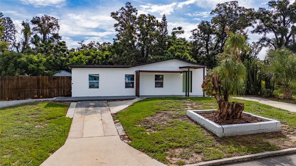 A white single-story house with a concrete walkway and a small tree in a planter — 5621 LUNSFORD DRIVE, ORLANDO, FL