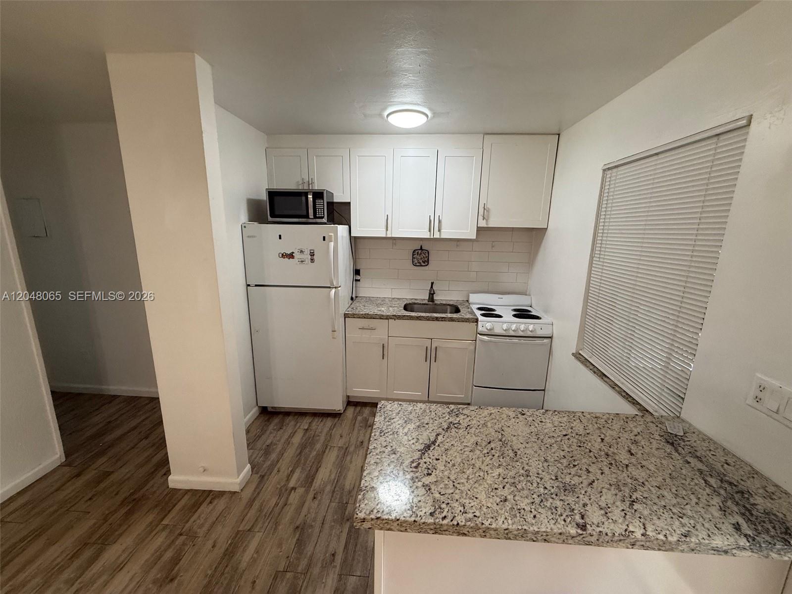 An open-concept kitchen and dining area features wood-look flooring and a ceiling fan — 34 SW 5th St # 2, Hallandale Beach FL 33009, HALLANDALE BEACH, FL