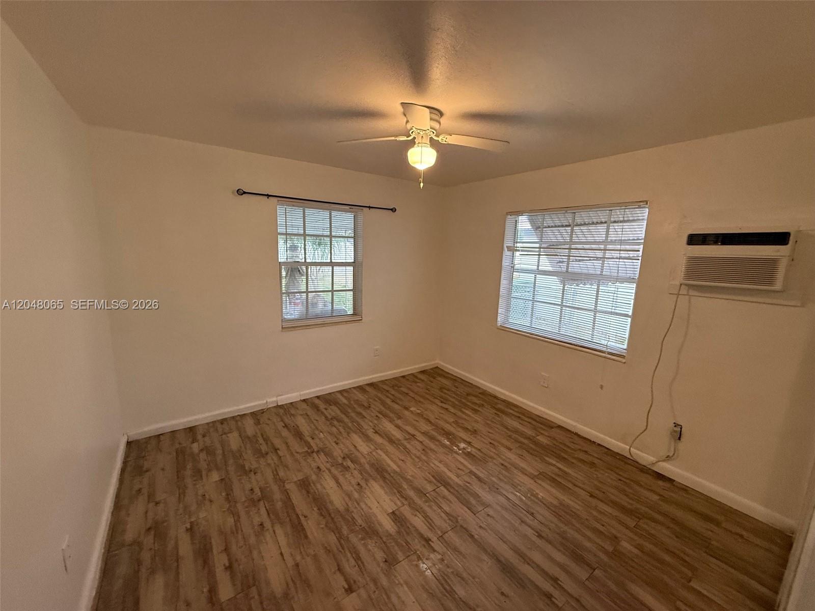 An open-concept kitchen and living area features wood-look flooring, white cabinetry, and a ceiling fan — 34 SW 5th St # 2, Hallandale Beach FL 33009, HALLANDALE BEACH, FL