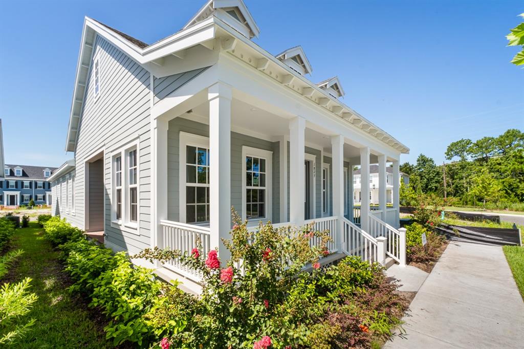 A light blue house with a covered front porch and white trim under a clear sky — 1827 HEADLAND LOOP, KISSIMMEE, FL