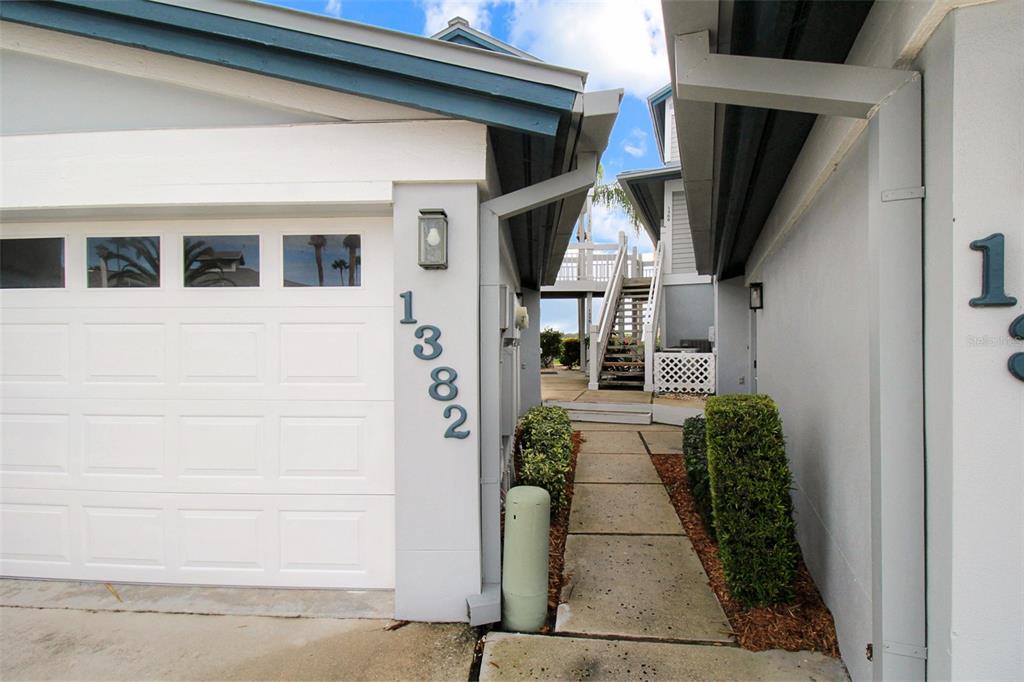 A white garage with house numbers and a walkway leading to an outdoor staircase — 1382 SIESTA BAYSIDE DRIVE UNIT 1382-C, SARASOTA, FL