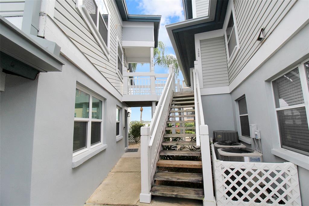 An outdoor staircase connects two gray buildings with a small bridge and lattice-enclosed air conditioners — 1382 SIESTA BAYSIDE DRIVE UNIT 1382-C, SARASOTA, FL