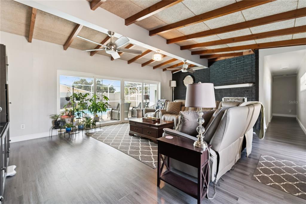 A living room features wood-beamed ceilings, a dark brick fireplace, and sliding glass doors — 2925 E LAKE HARTRIDGE DRIVE, WINTER HAVEN, FL