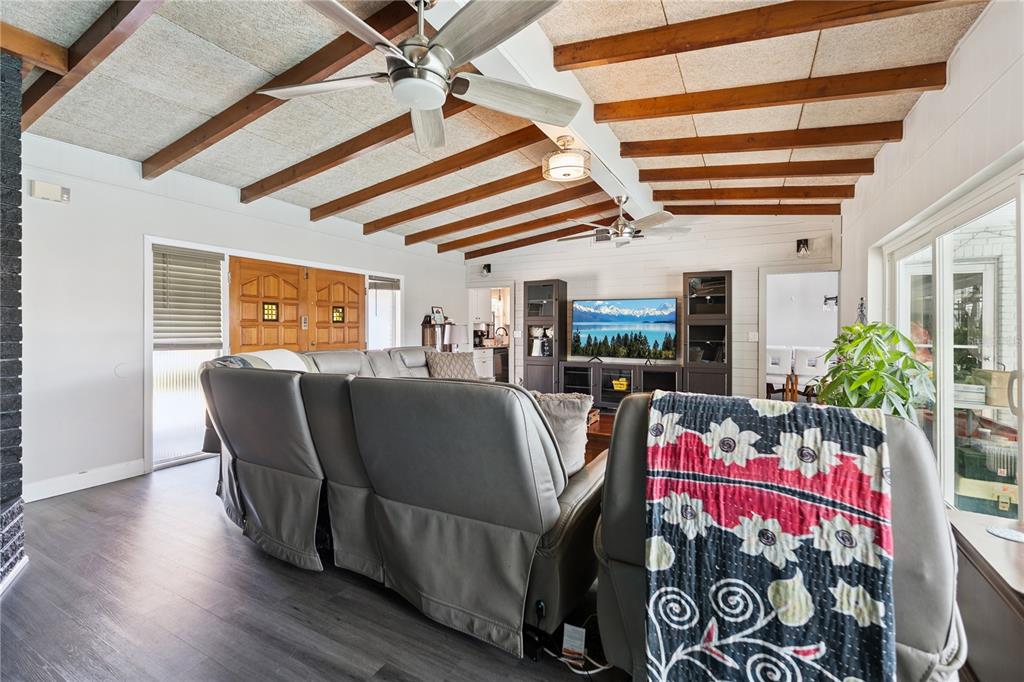 A living room features a grey sectional sofa, wood-beamed ceiling, and dark wood flooring — 2925 E LAKE HARTRIDGE DRIVE, WINTER HAVEN, FL