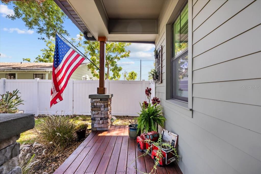 A wooden porch features a stone pillar, an American flag, and a decorative red truck planter — 3804 N DARWIN AVENUE, TAMPA, FL