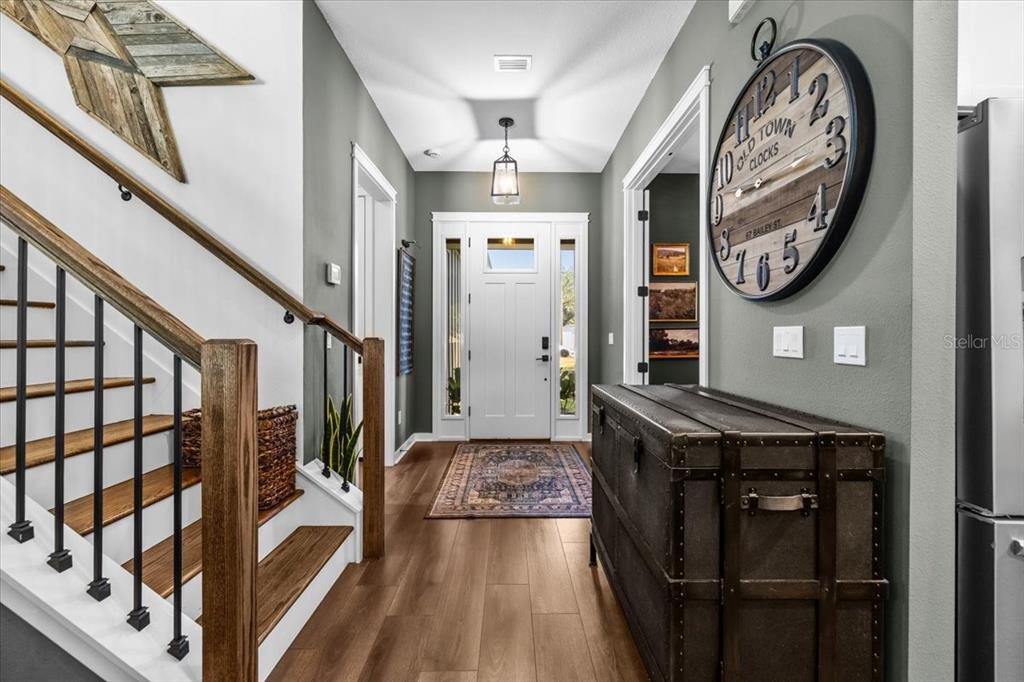 A foyer features wood flooring, a staircase with iron railings, and a large wall clock — 3804 N DARWIN AVENUE, TAMPA, FL