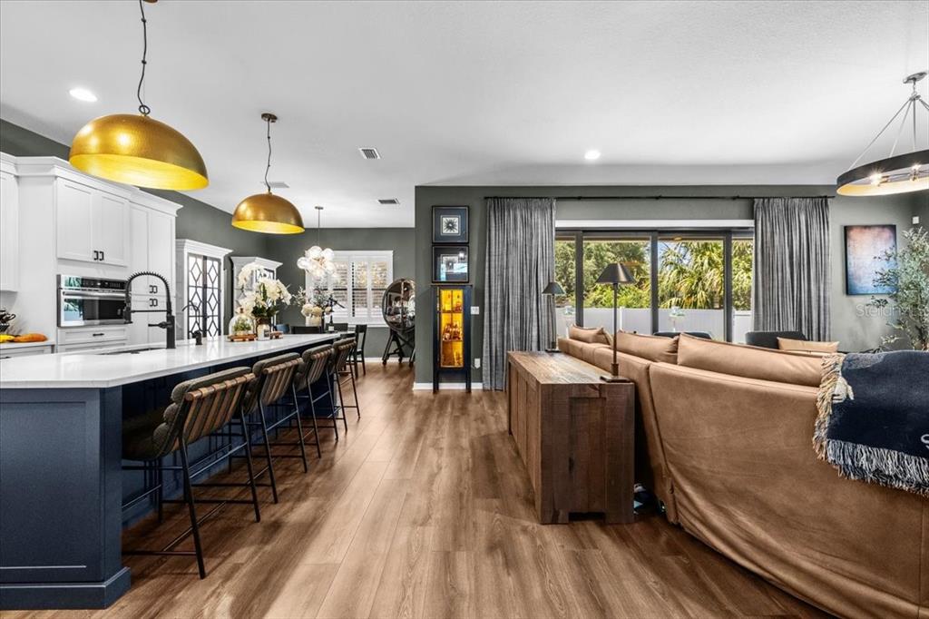 A kitchen with a blue island and gold pendant lights opens to a living area — 3804 N DARWIN AVENUE, TAMPA, FL