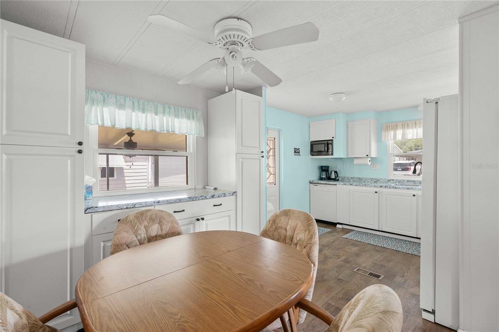 A kitchen with white cabinets, a round wooden dining table, and light blue walls — 36650 DINA DRIVE, ZEPHYRHILLS, FL