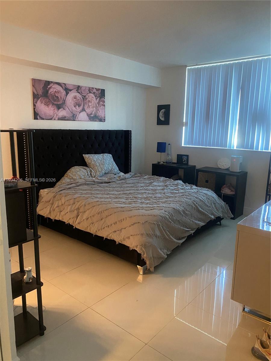 A bedroom features a tufted black headboard, a textured beige comforter, and white tile flooring — 1861 NW S River Dr # 2307, Miami FL 33125, MIAMI, FL