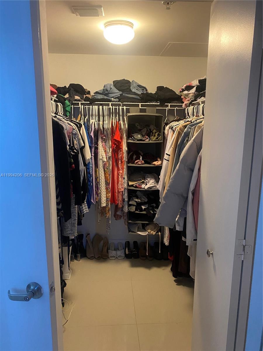 A walk-in closet features hanging clothes, a central shelving unit, and tile flooring — 1861 NW S River Dr # 2307, Miami FL 33125, MIAMI, FL