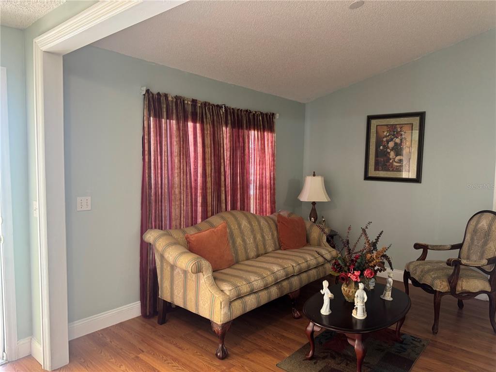 A living room features a striped sofa, a dark wood coffee table, and patterned curtains — 1112 ROAN COURT, KISSIMMEE, FL