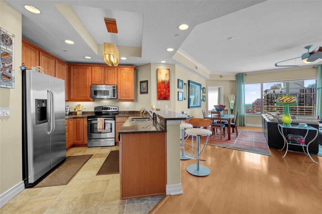 A kitchen with wood cabinets and stainless steel appliances opens to a living and dining area — 449 S 12TH STREET UNIT 2205, TAMPA, FL