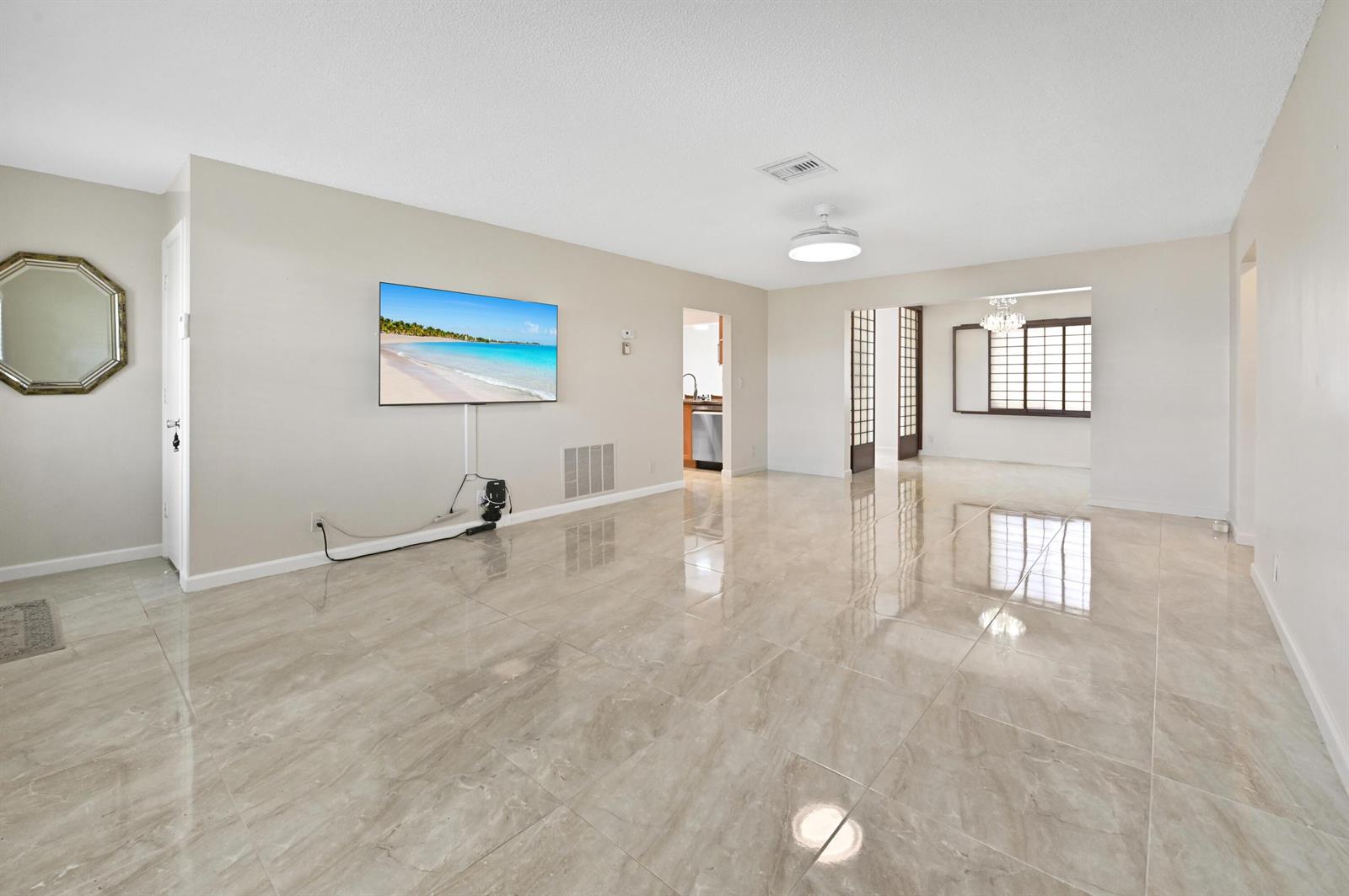 A spacious living room features glossy tile flooring, a wall-mounted television, and an adjacent dining area — 2012 SW 17th Avenue, Boynton Beach FL 33426, BOYNTON BEACH, FL