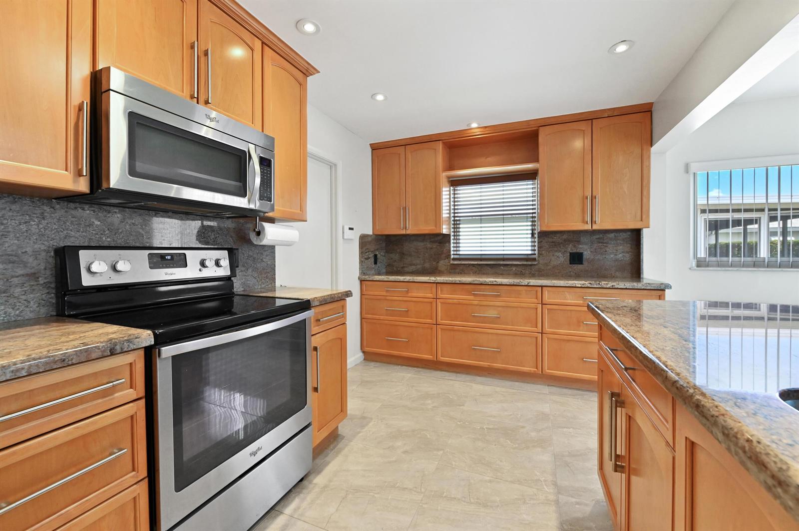 A kitchen features wood cabinets, granite countertops, stainless steel appliances, and light tile flooring — 2012 SW 17th Avenue, Boynton Beach FL 33426, BOYNTON BEACH, FL