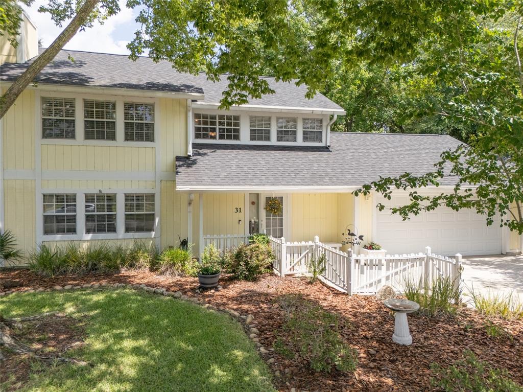A two-story yellow house with a white fence, garage, and landscaped front yard — 31 WENDOVER LANE, PALM COAST, FL