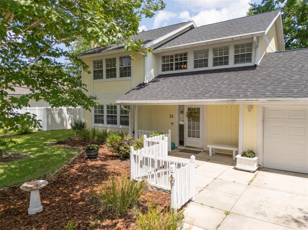 A two-story yellow house with a white picket fence and a concrete driveway — 31 WENDOVER LANE, PALM COAST, FL