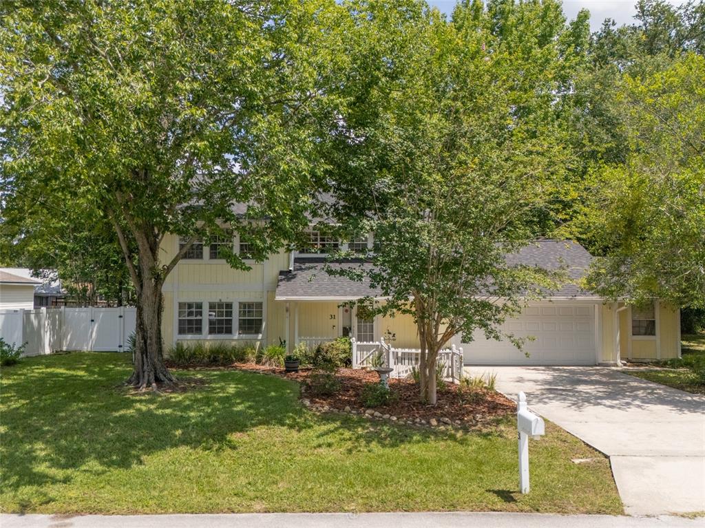 A two-story yellow house with a white garage and a large tree in the yard — 31 WENDOVER LANE, PALM COAST, FL