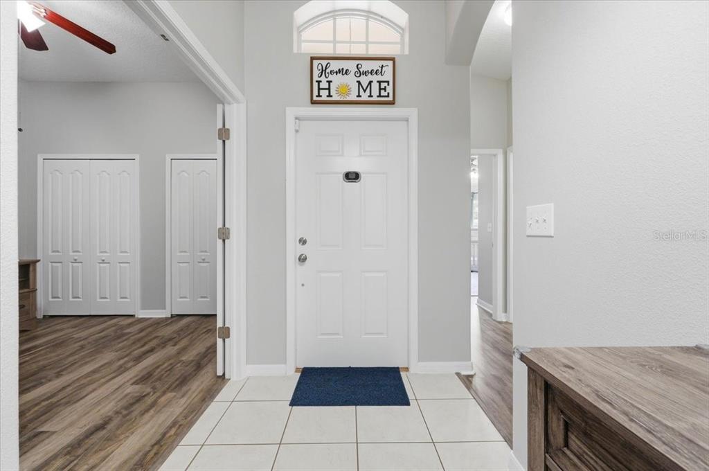 A bright entryway features a white front door, tiled floor, and light gray walls — 4661 HICKORY STREAM LANE, MULBERRY, FL