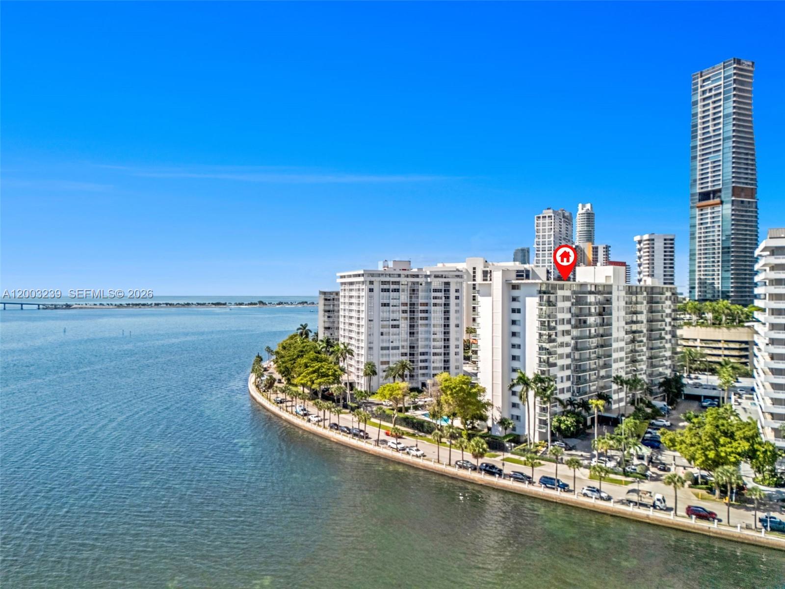 An aerial view shows waterfront apartment buildings along a coastline under a clear blue sky — 1408 Brickell Bay Dr # 518, Miami FL 33131, MIAMI, FL