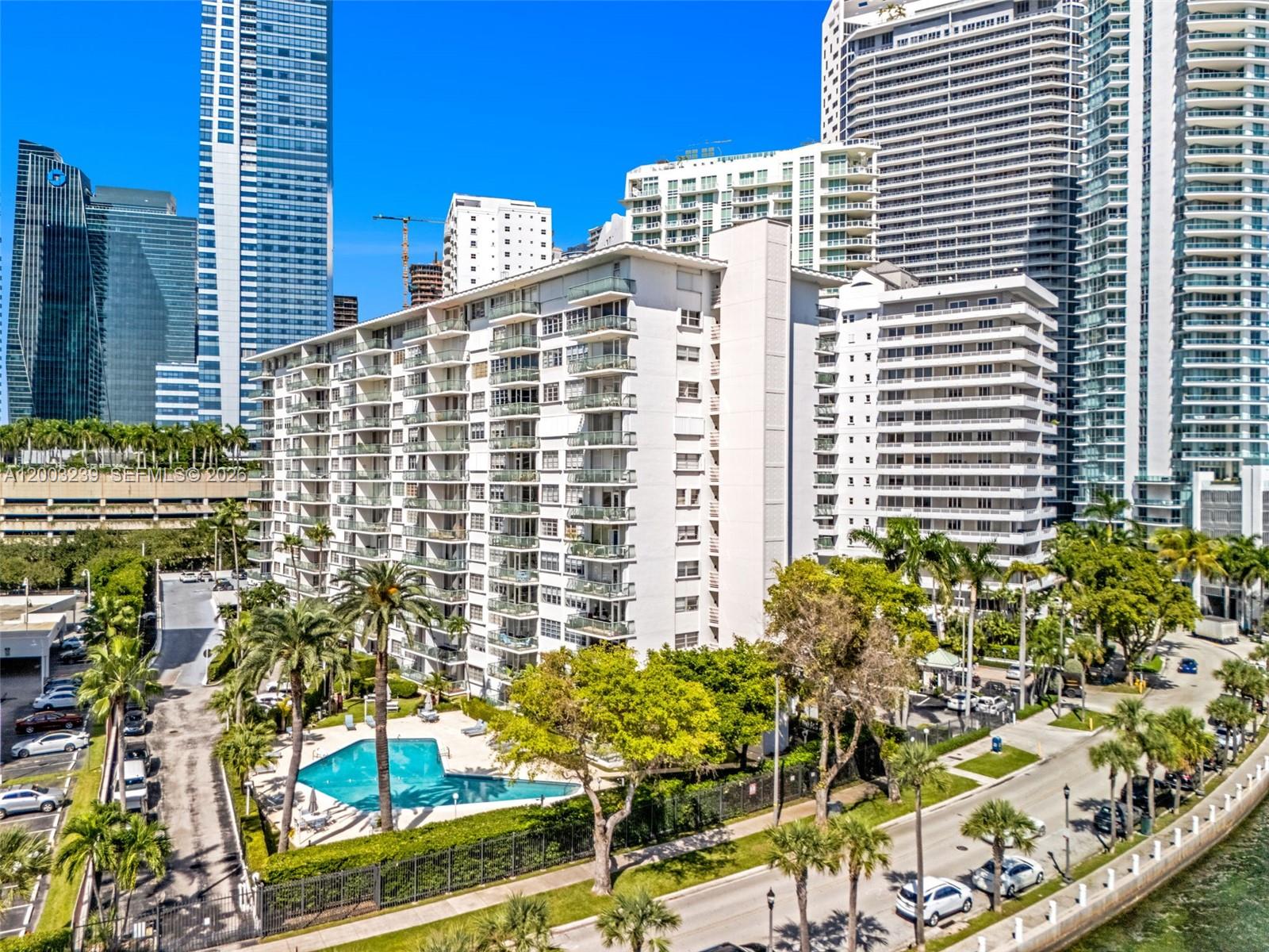 An aerial view shows a white multi-story apartment building with a swimming pool and palms — 1408 Brickell Bay Dr # 518, Miami FL 33131, MIAMI, FL