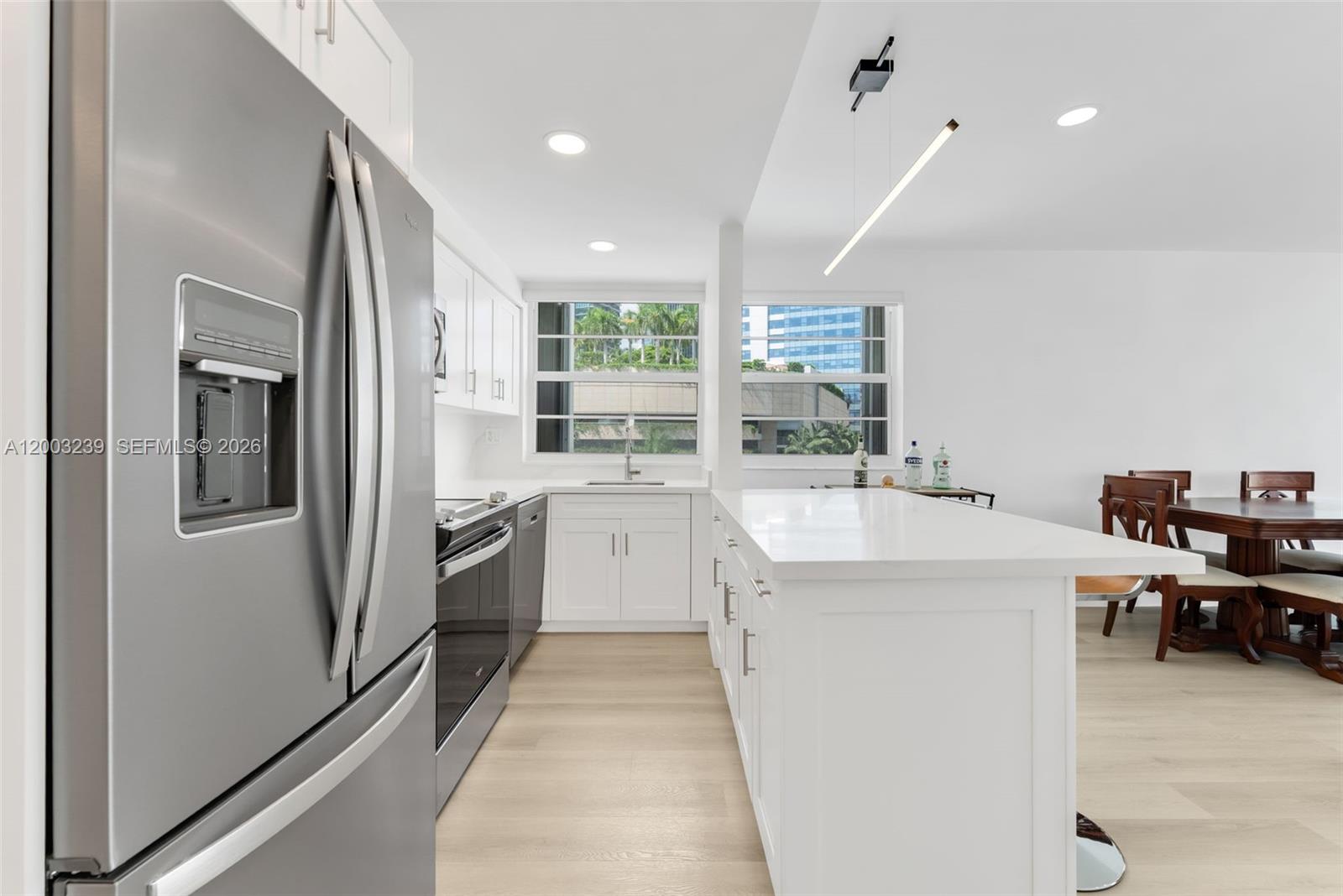 A modern kitchen features white cabinetry, a large island, stainless steel appliances, and light flooring — 1408 Brickell Bay Dr # 518, Miami FL 33131, MIAMI, FL