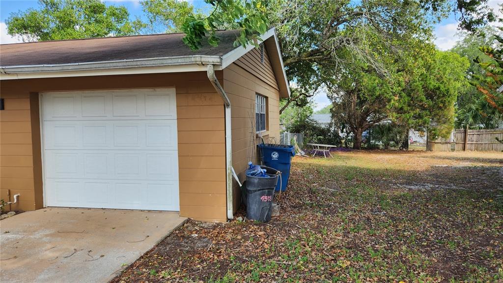 A tan house with a white garage door and two trash cans outside — 4518 YORKSHIRE AVENUE, SPRING HILL, FL