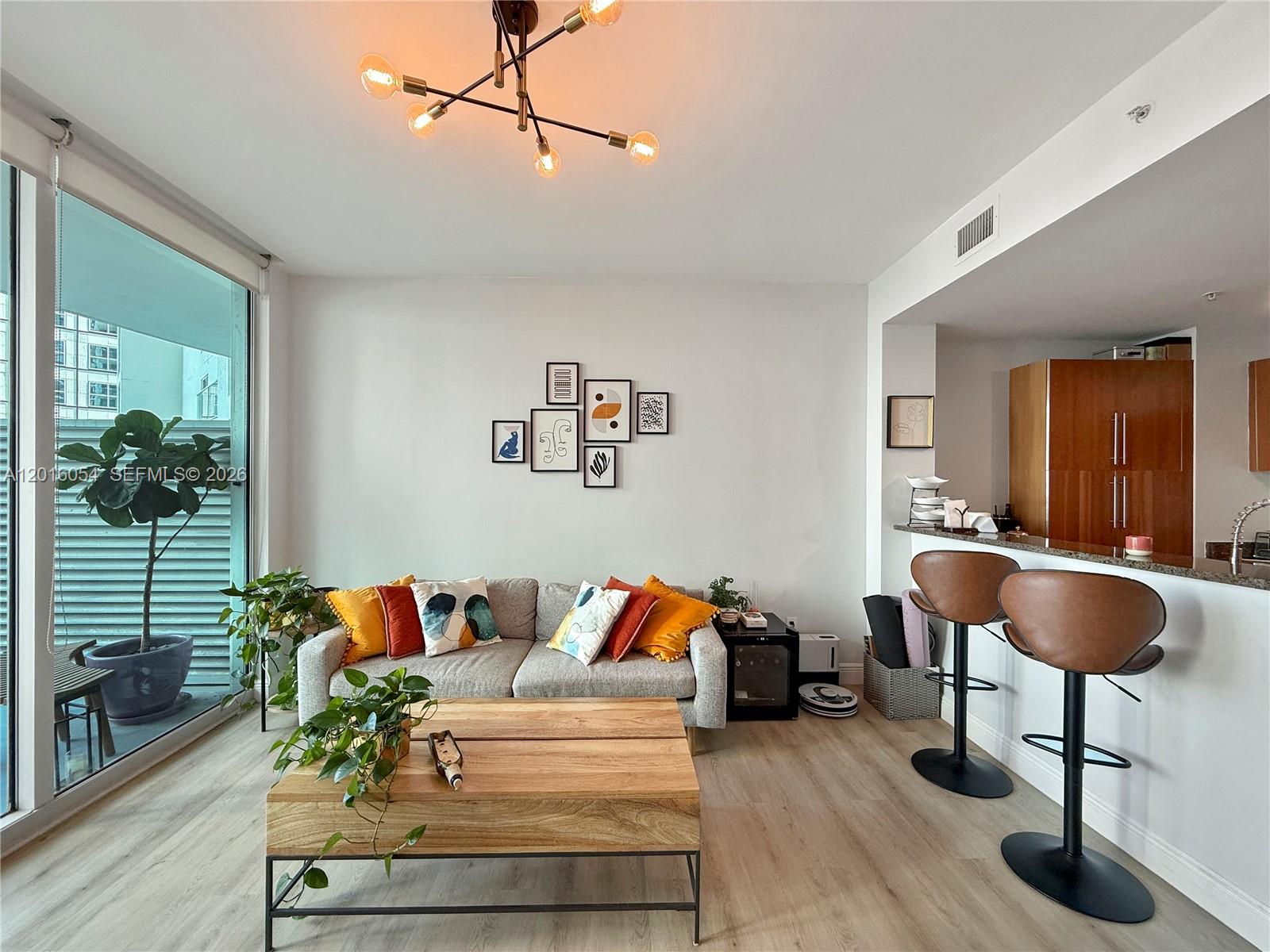 A living room features a grey sofa, wooden coffee table, and a breakfast bar — 300 S Biscayne Blvd # 1705, Miami FL 33131, MIAMI, FL