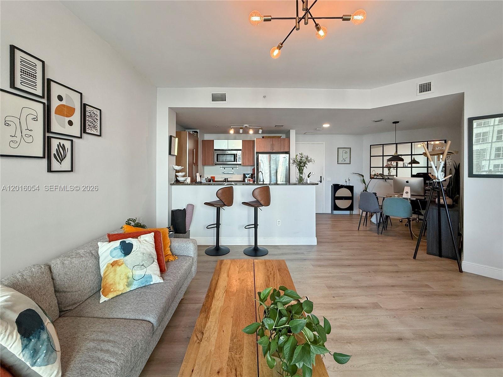 A modern living room features a desk, sofa, coffee table, and a balcony with city views — 300 S Biscayne Blvd # 1705, Miami FL 33131, MIAMI, FL