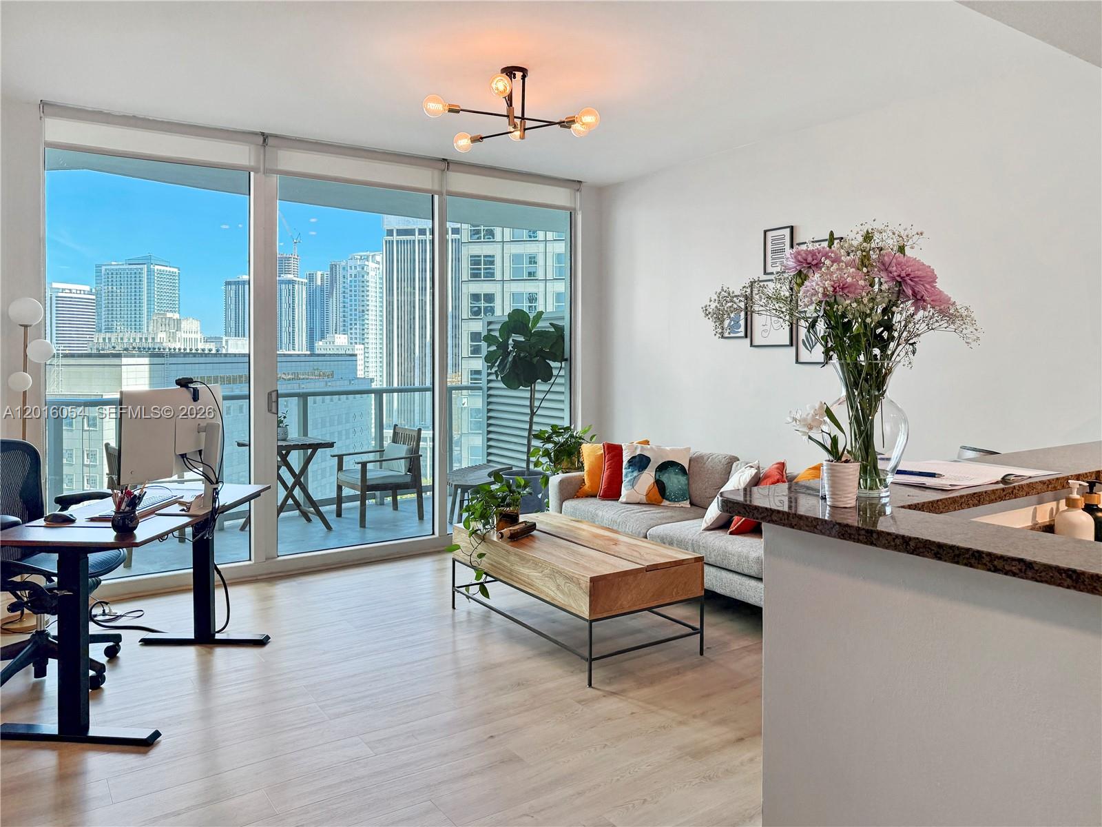 An open-concept living area features a kitchen, dining space, and balcony with city views — 300 S Biscayne Blvd # 1705, Miami FL 33131, MIAMI, FL