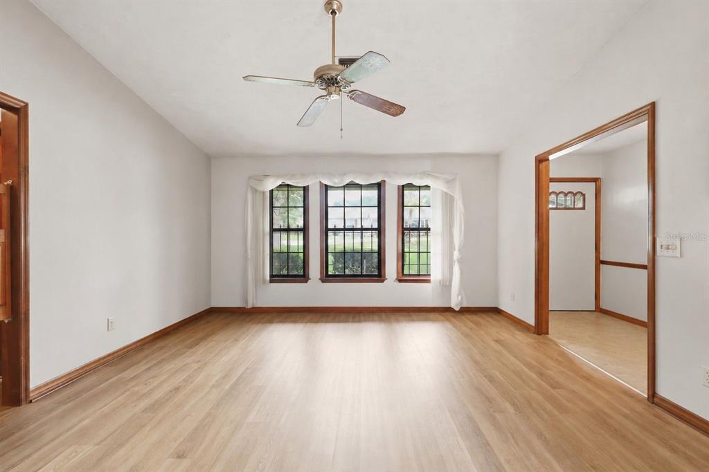 An empty room with light wood-look flooring, white walls, a ceiling fan, and three windows — 2360 DARTMOUTH ROAD, DELAND, FL