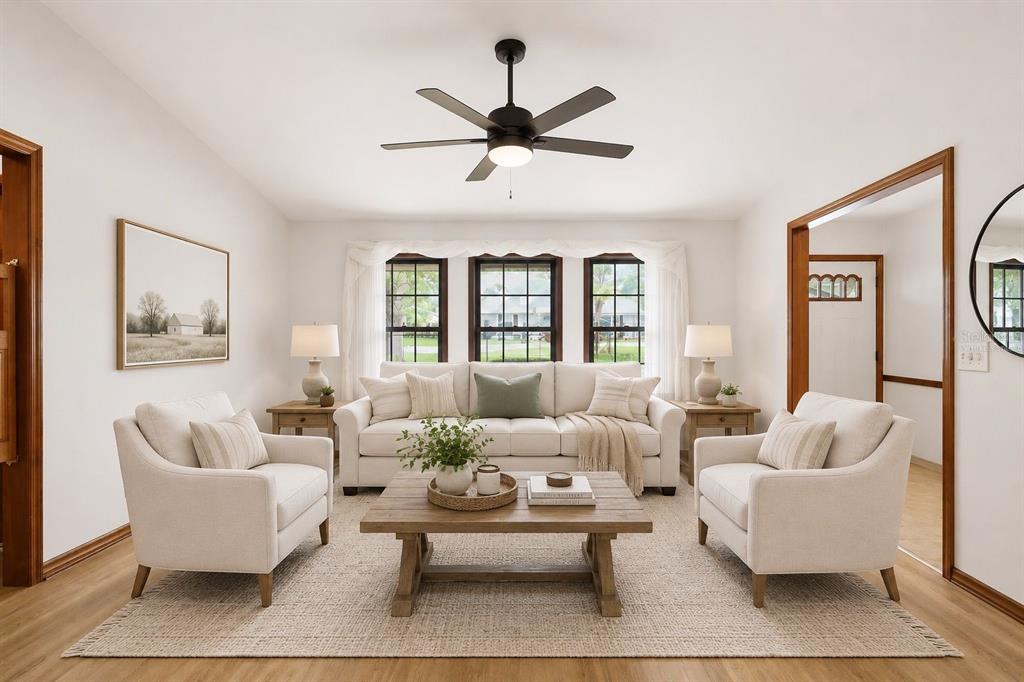 A bright living room features a white sofa, two armchairs, a wooden coffee table, and windows — 2360 DARTMOUTH ROAD, DELAND, FL