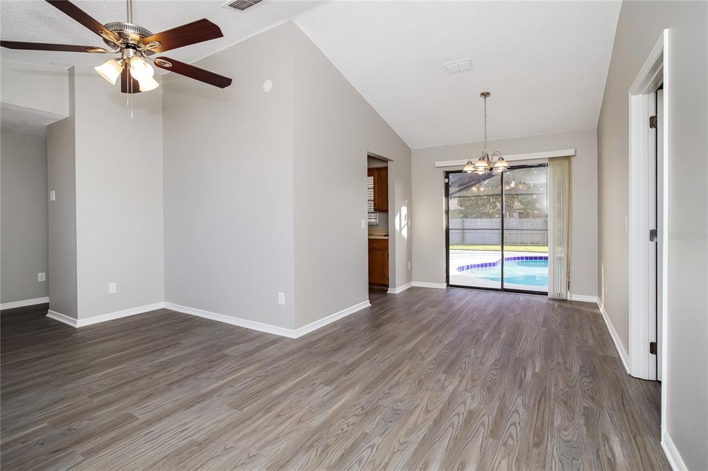A living area with wood-look flooring, a ceiling fan, and sliding doors to a pool — 24 BRADFORD COURT, KISSIMMEE, FL