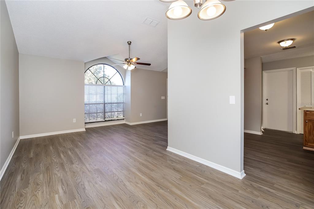 An empty room with gray walls, wood-look flooring, a ceiling fan, and an arched window — 24 BRADFORD COURT, KISSIMMEE, FL