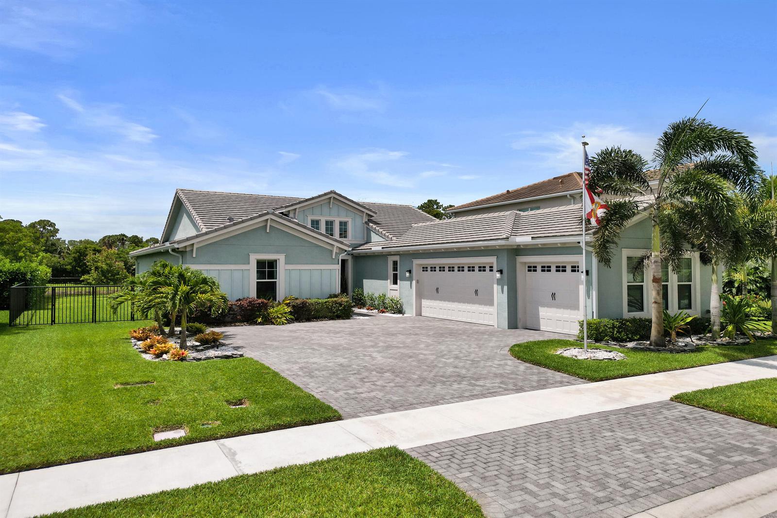 A light blue single-story house with a paver driveway, three-car garage, and a palm tree — 15822 Orchard Drive, Westlake FL 33470, WESTLAKE, FL
