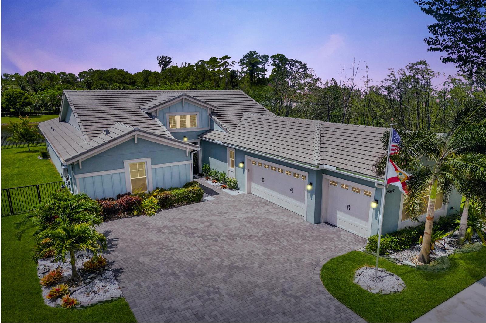 An aerial view of a blue house with a paved driveway and a three-car garage — 15822 Orchard Drive, Westlake FL 33470, WESTLAKE, FL