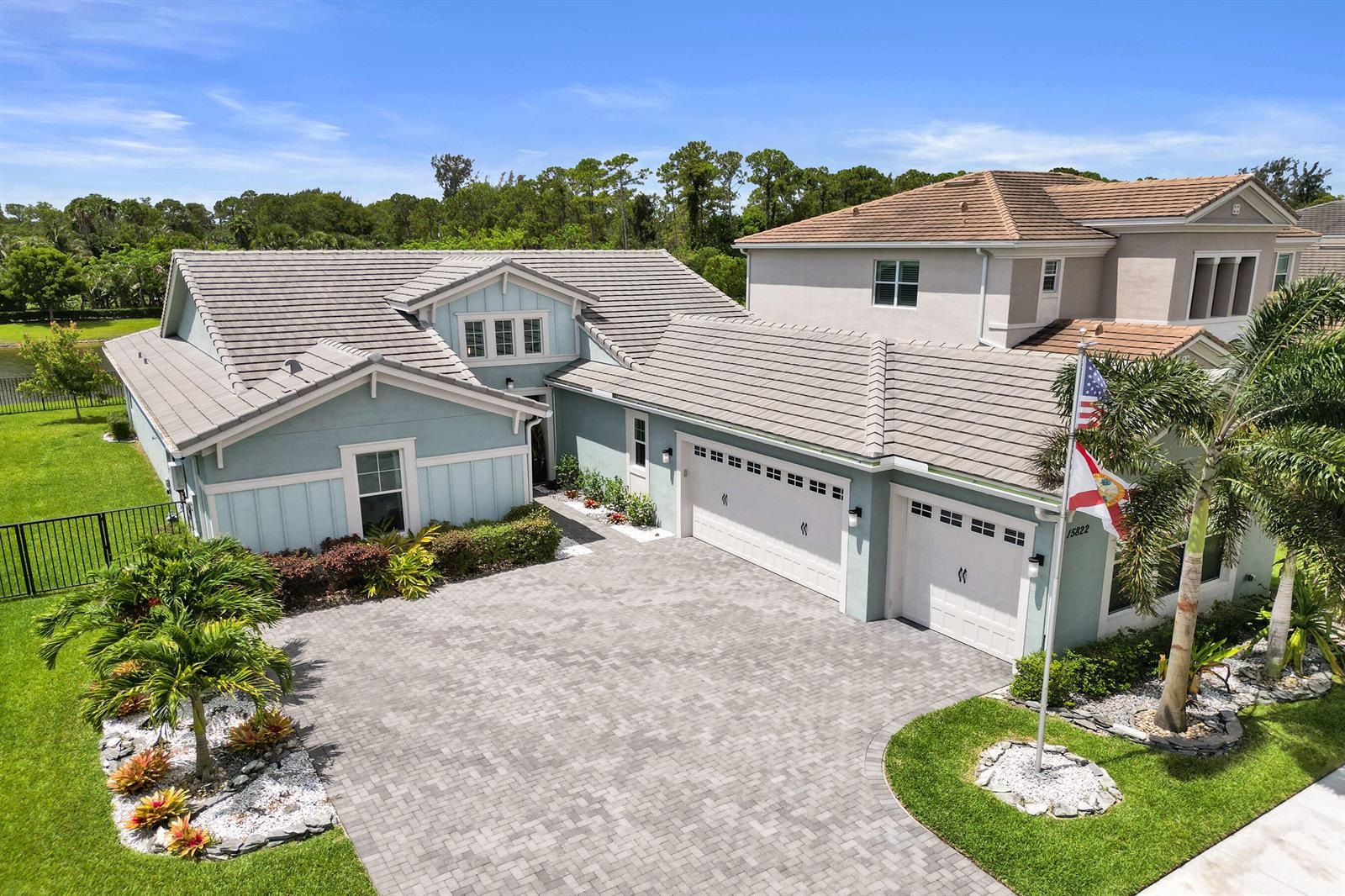An aerial view shows a light blue house with a tiled roof and a paved driveway — 15822 Orchard Drive, Westlake FL 33470, WESTLAKE, FL