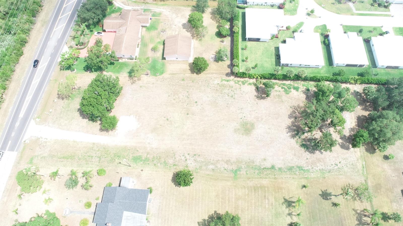 An aerial view shows a vacant, rectangular grassy lot situated between several residential properties — 4716 58th Avenue, Vero Beach FL 32967, VERO BEACH, FL