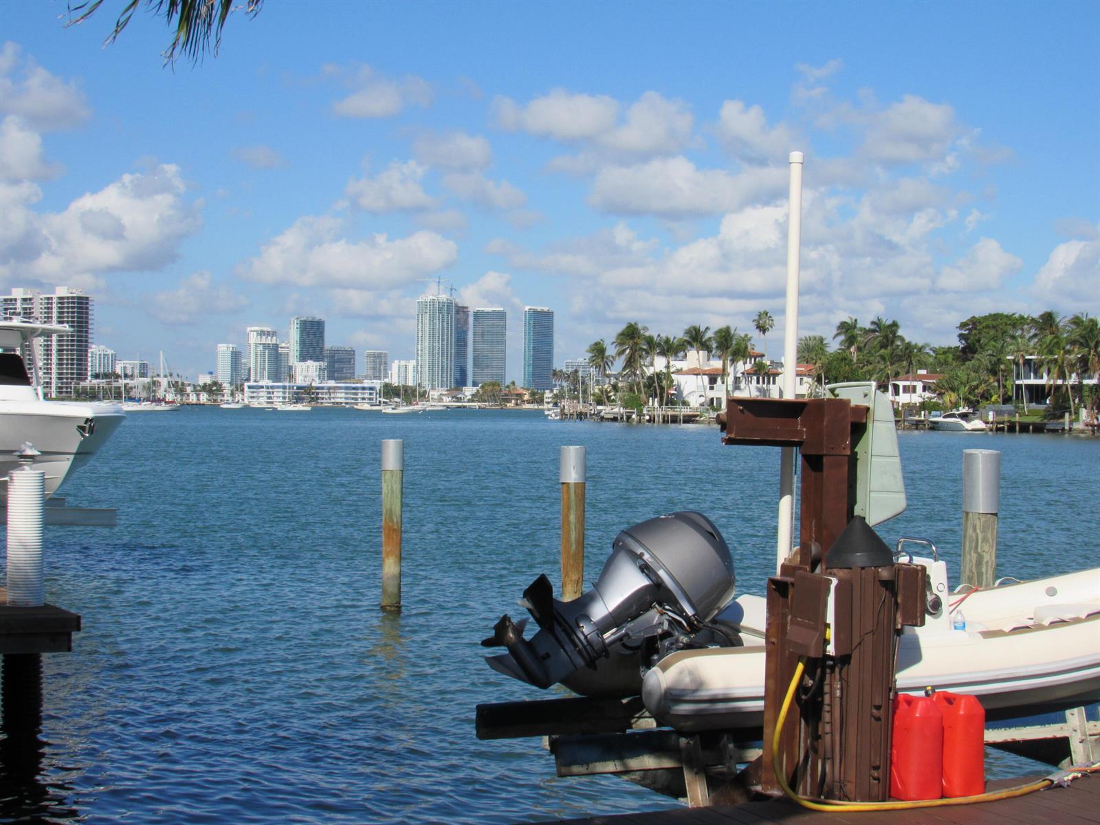 A view of a waterfront dock with boats and a distant city skyline under clouds — 185 Palm Avenue, Miami Beach FL 33139, MIAMI BEACH, FL