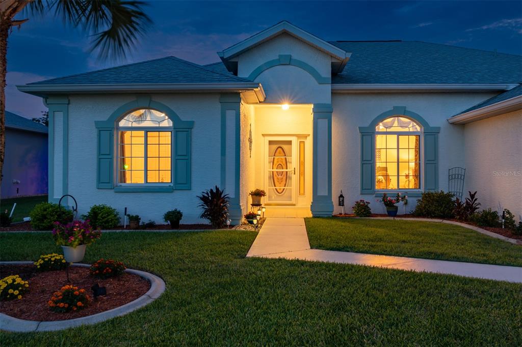 A single-story house with a white stucco exterior, teal shutters, and a front walkway — 2291 NW 59TH TERRACE, OCALA, FL