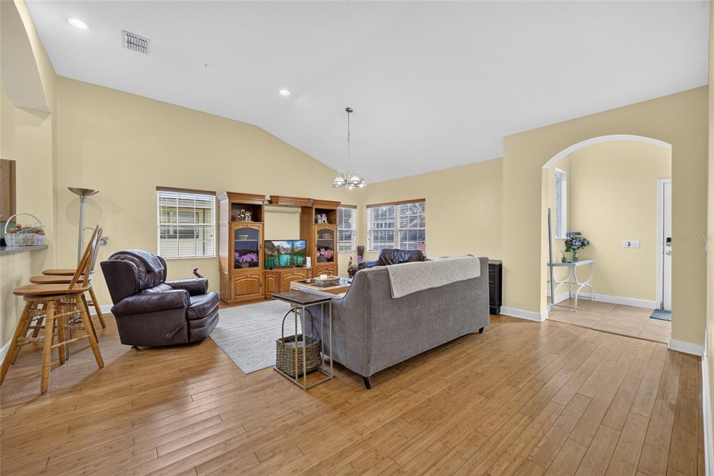 A living room features light yellow walls, wood flooring, a vaulted ceiling, and an arched entryway — 125 PAGE STREET, ORLANDO, FL