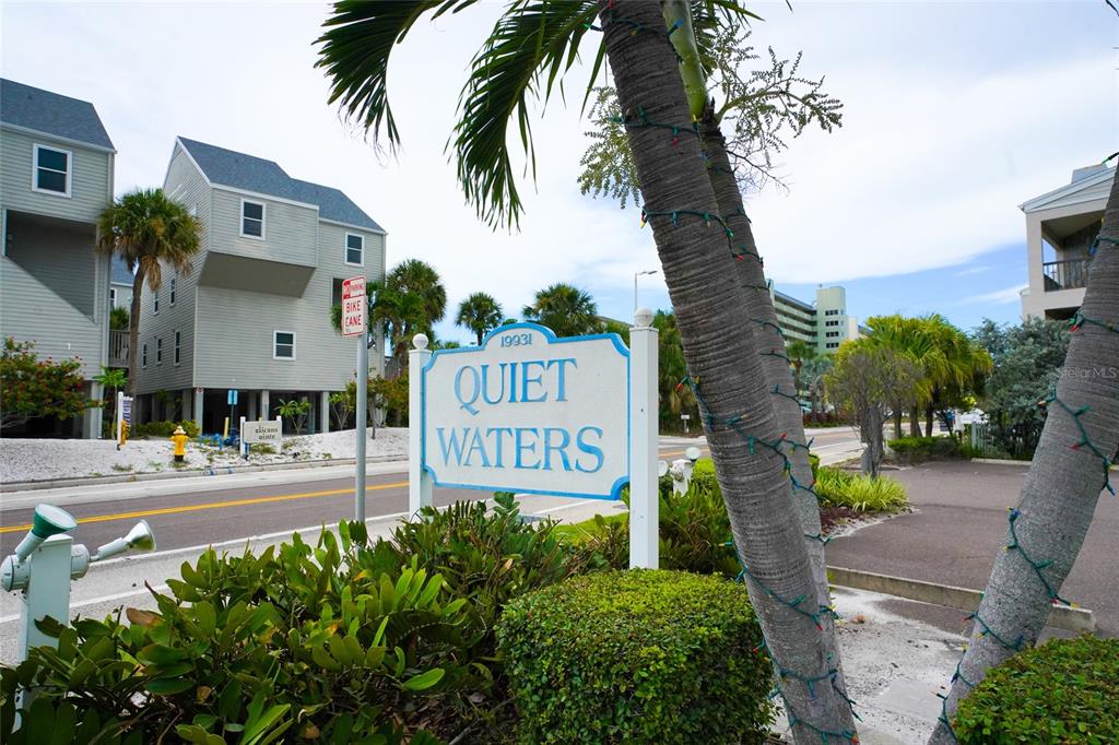 A sign for Quiet Waters stands in front of multi-story houses and palm trees — 19931 GULF BOULEVARD UNIT D2, INDIAN SHORES, FL