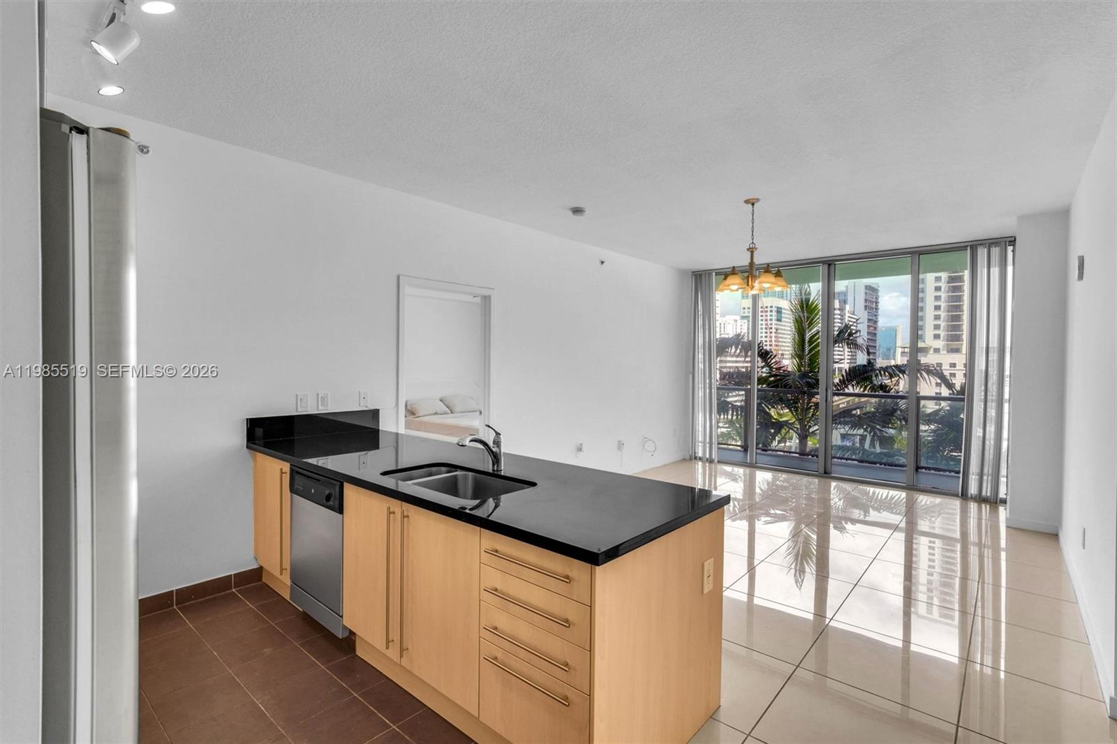 A kitchen island with black countertops sits in an open-plan living area with tile floors — 79 SW 12th St # 1210, Miami FL 33130, MIAMI, FL