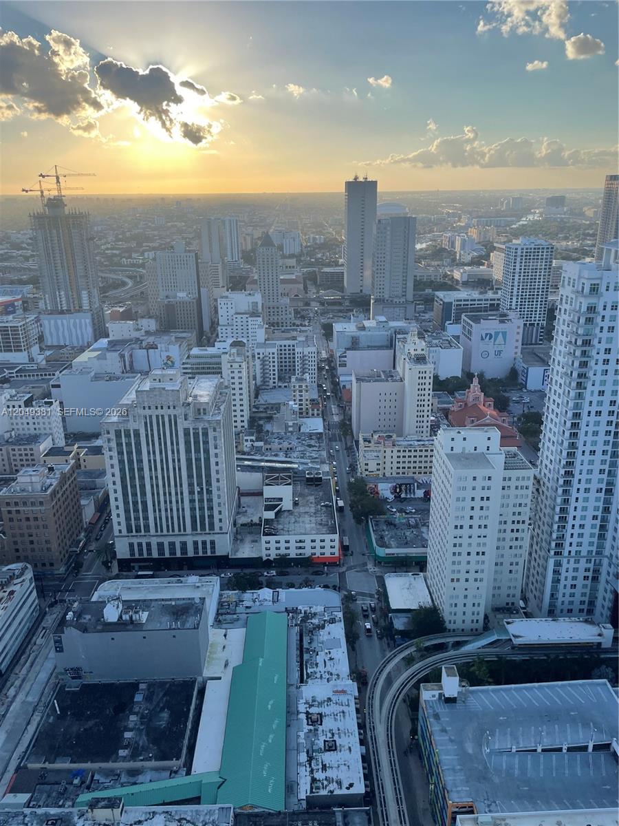 An elevated view of a dense city skyline at sunset with a visible monorail track — 50 Biscayne Blvd # 5001, Miami FL 33132, MIAMI, FL