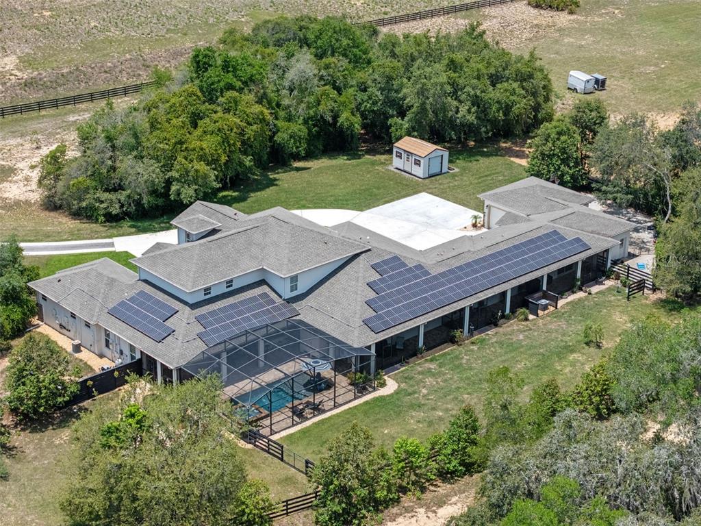 An aerial view shows a large house with solar panels, a screened pool, and a shed — 20199 SWEETWOOD LANE, CLERMONT, FL