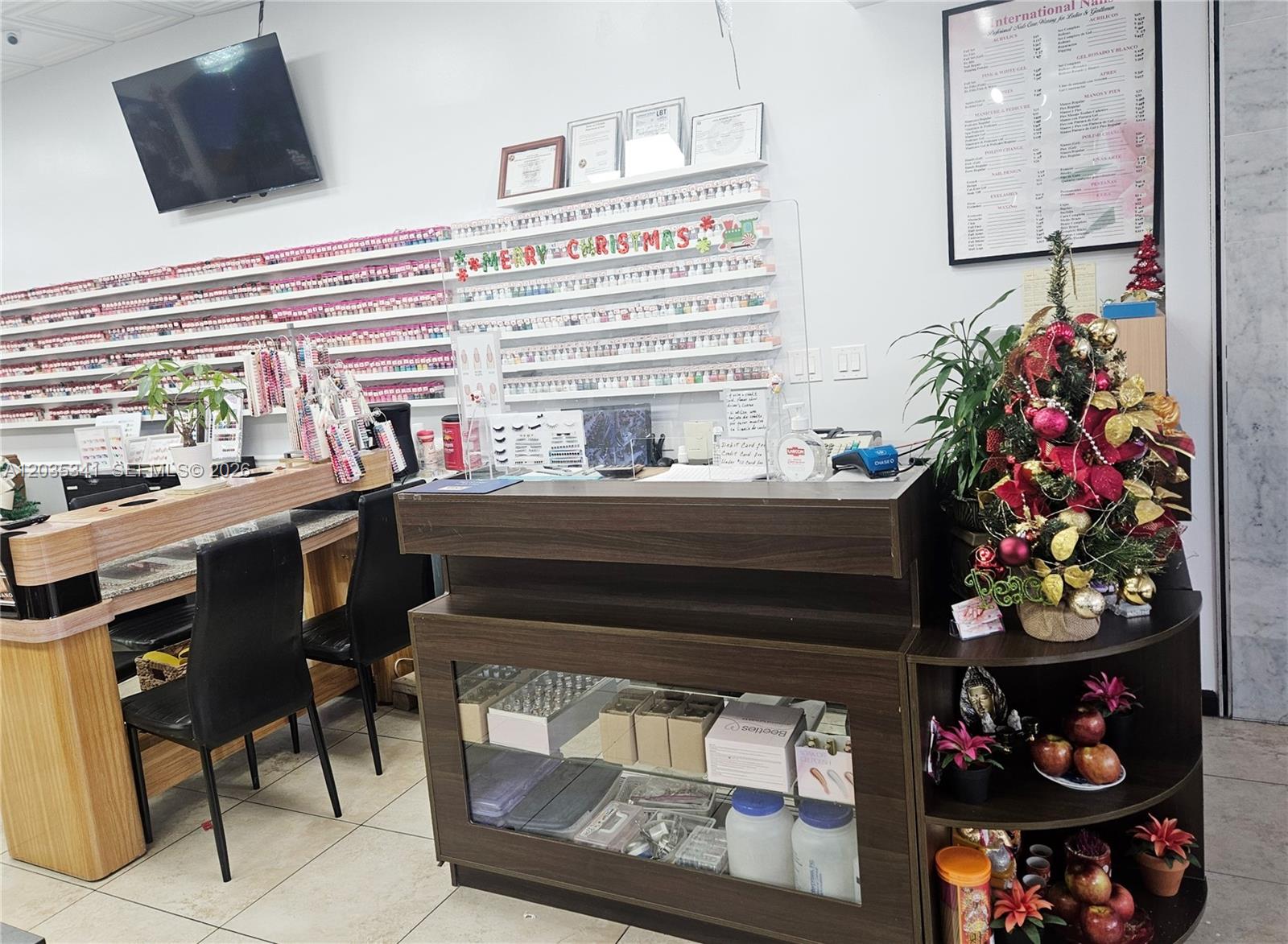 A nail salon reception desk sits in front of shelves filled with nail polish bottles — 1455 NW 107, Doral FL 33172, DORAL, FL