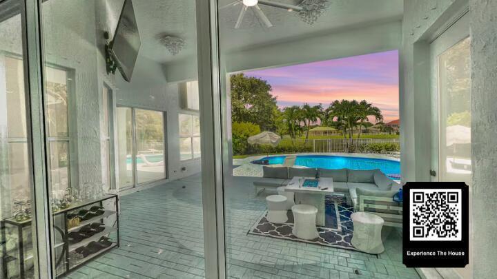 A covered patio features a seating area, a swimming pool, and a sunset view — 11910 Osprey Point Circle, Wellington FL 33449, WELLINGTON, FL